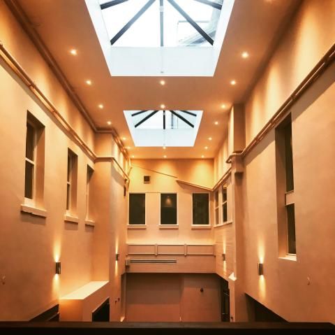 Atrium lit with warm wall lights under a roof lantern